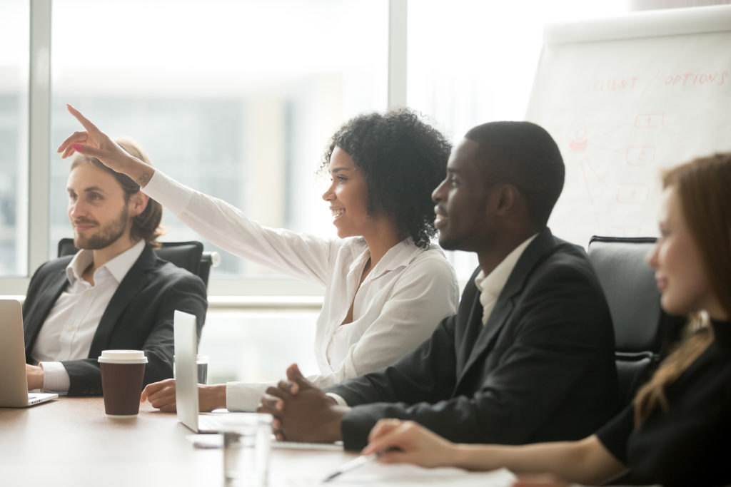 African woman raising hand to ask question at team training, curious black employee or conference seminar participant vote as volunteer at group office meeting with multiracial diverse businesspeople